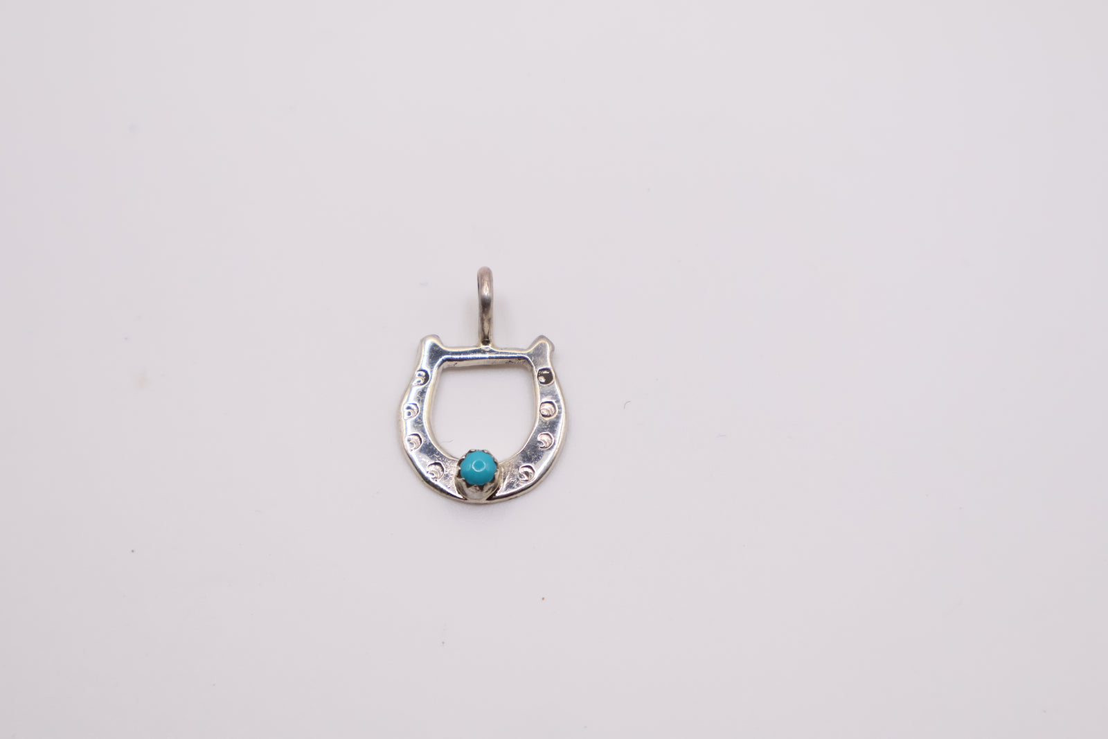 sterling silver horseshoe pendant features a centered turquoise stone and often resembles handcrafted Navajo designs