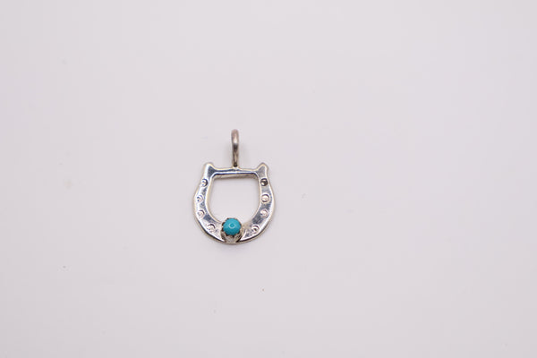 Native American sterling silver horseshoe pendant features a centered turquoise stone and often resembles handcrafted Navajo designs