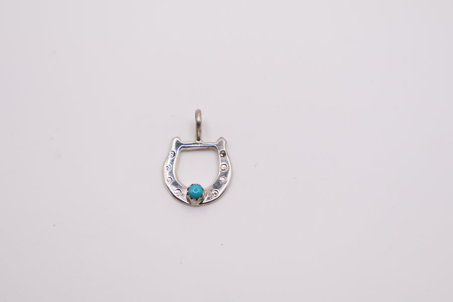 Native American sterling silver horseshoe pendant features a centered turquoise stone and often resembles handcrafted Navajo designs